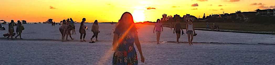 Two women walking on the beach at sunset.